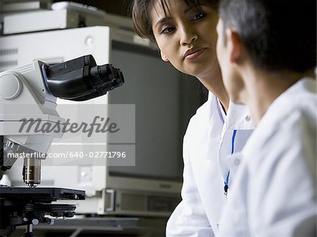 Technicien de laboratoire femelles regardant au microscope avec technicien mâle