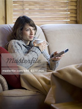 Femme sur le canapé avec une tasse de café