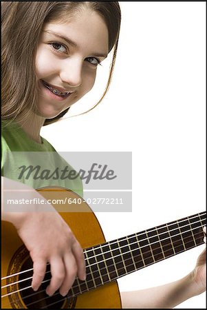 Fille avec bretelles jouant guitare souriant