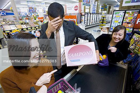 Homme à la caisse épicerie avec boîte de tampons et de deux femmes