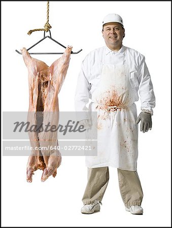 Butcher standing with hanging carcass and knife