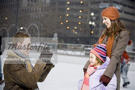 Man taking picture of woman and girl outdoors in winter