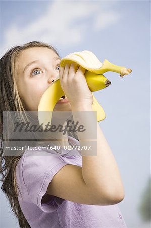 Jeune fille mange banane Photographie de stock Masterfile