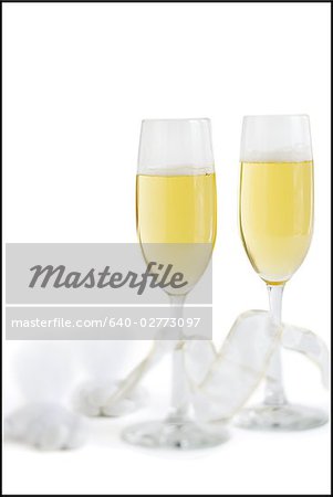 Two champagne flutes with champagne and ribbons with hard candies