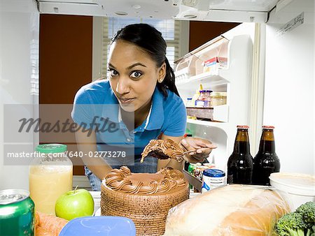 Femme secrètement prendre morceau de gâteau au chocolat de réfrigérateur