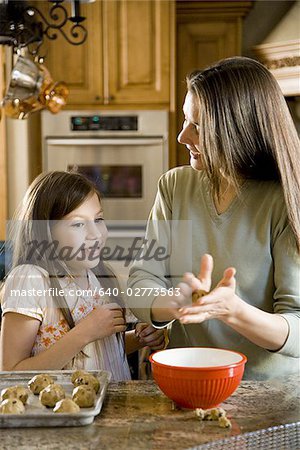 Girl in kitchen with woman baking cookies