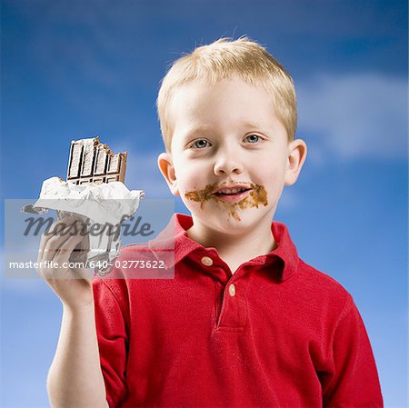 Garçon, manger une barre chocolatée avec ciel bleu