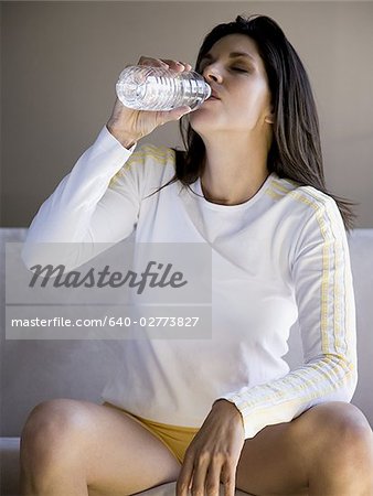Woman sitting on sofa drinking bottled water