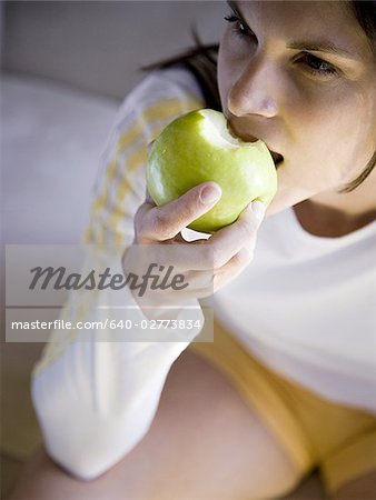 Woman sitting and eating green apple