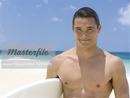 Man with surfboard on beach smiling