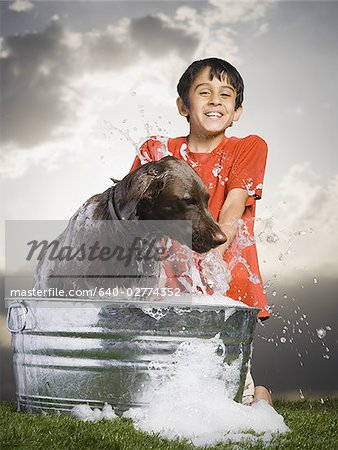 Boy bathing dog outdoors smiling