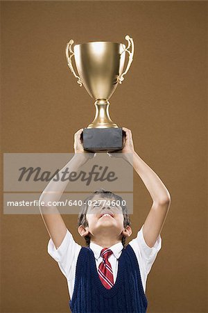 Boy holding Trophäe Pokal über Kopf lächelnd