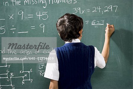 Vue arrière du garçon au tableau faisant des formules mathématiques