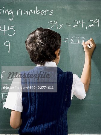 Rear view of boy at chalkboard doing math formulas