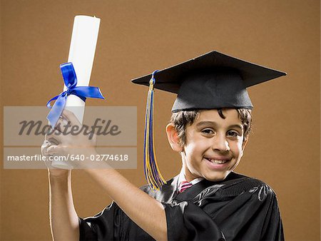 Boy graduate with mortar board and diploma smiling