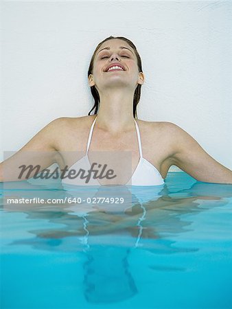 Frau sitzt im Pool mit Knien sich unter Ton-Urne