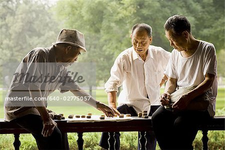 Drei Männer spielen im freien lächelnd Brettspiel