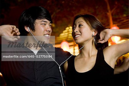 Couple à l'écoute de mp3 player en plein air, danse et souriant