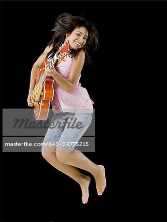 Femme avec guitare sautant et souriant