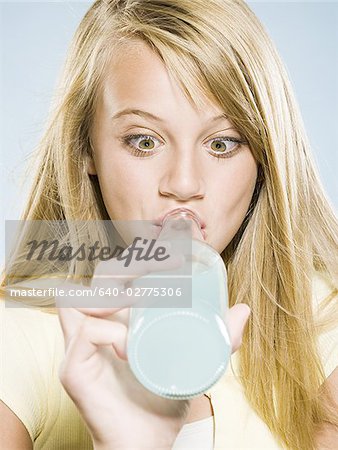 Girl drinking soda from bottle with eyes crossed