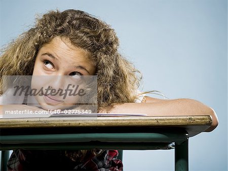 Girl leaning on desk with workbook smiling