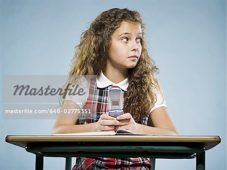 Fille assise au comptoir avec classeur et téléphone cellulaire