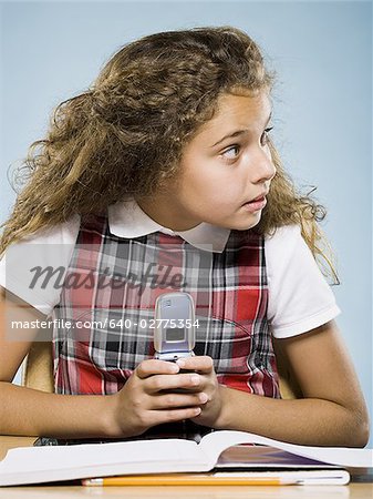 Fille assise au comptoir avec classeur cachant de téléphone cellulaire