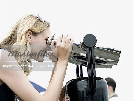 Profil von Woman looking through Münze betrieben Fernglas lächelnd