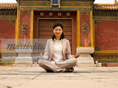 Businesswoman sitting cross legged outdoors meditating