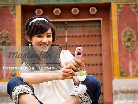 Teenage girl sitting outdoors with cell phone