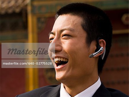 Homme d'affaires avec casque d'écoute en souriant à l'extérieur