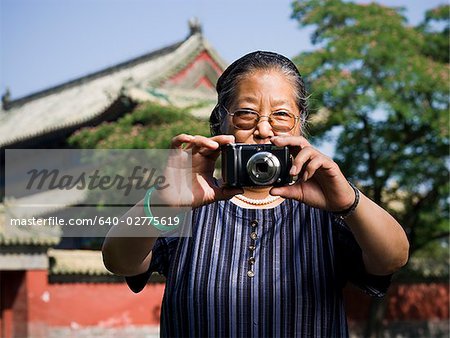 Mature woman with camera outdoors smiling