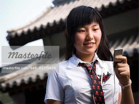 Adolescente en uniforme scolaire, sourire avec lecteur mp3