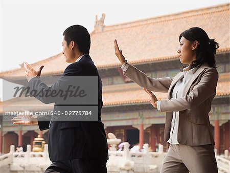 Businesswoman and man doing tai chi outdoors