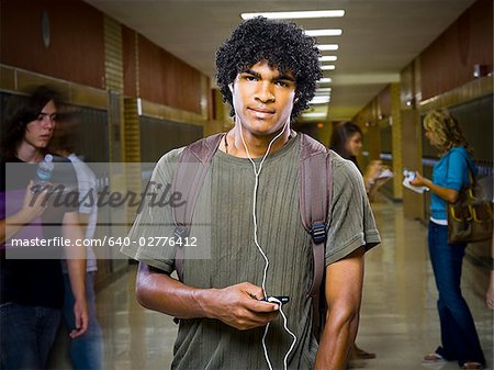 High School boy at school listening to MP3 player.