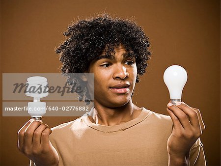 young man in a brown shirt holding light bulbs.