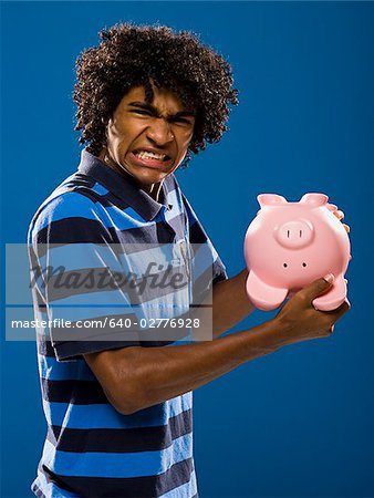 junger Mann versucht, Geld aus einem Sparschwein.