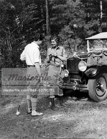 1930s COUPLE MAN WOMAN IN FISHING GEAR HOLDING POLES STANDING IN FRONT OF CAR