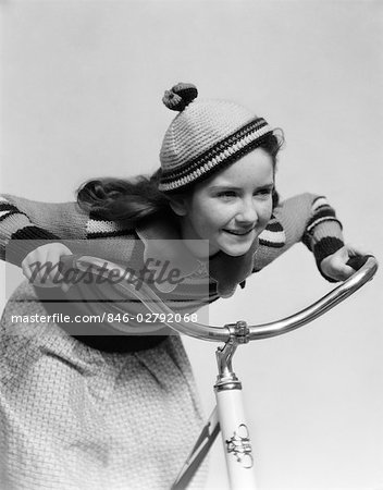 ANNÉES 1930 SOURIANT AVIDE LITTLE GIRL IN TRICOT CAP ET CORRESPONDANCE LEANING BIKE RIDING CHANDAIL AU GUIDON