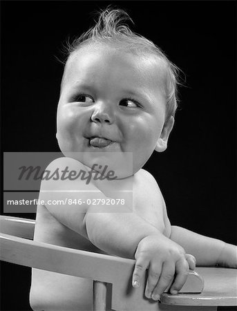 1940ER JAHRE BABY IM HOCHSTUHL KOPF WANDTE SICH AN EINER SEITE MIT ZUNGE RAGTE DUMME GLÜCKLICH LUSTIG AUSDRUCK