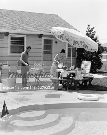 1960s FAMILY OF FOUR BACKYARD BARBEQUE BY POOL FATHER GRILLING MOTHER SERVING LEMONADE TO SON AND DAUGHTER SUMMER OUTDOOR