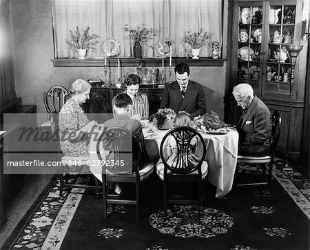 1940s EXTENDED FAMILY SITTING AROUND DINING ROOM TABLE SAYING GRACE BEFORE THANKSGIVING DINNER