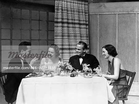 ANNÉES 1930 DES ANNÉES 1920, DEUX COUPLES HOMMES FEMMES DÎNER MANGER TENUE DE VILLE