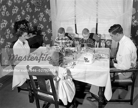 ANNÉES 1950 FAMILLE 5 MAMAN PAPA 3 ENFANTS ASSIS À LA SALLE À MANGER TABLE DISANT GRACE À TÊTES S'INCLINA