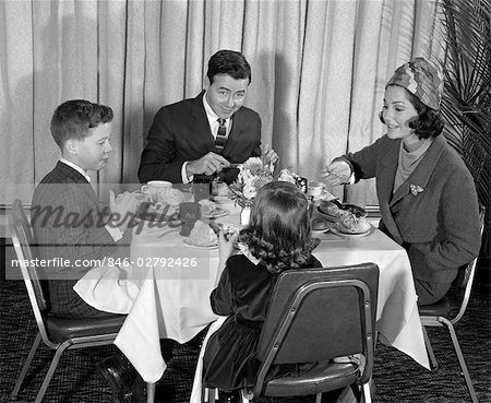 1960s FAMILY OF 4 SEATED AT TABLE IN FORMAL ATTIRE EATING DINNER & HAVING CONVERSATION