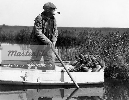 1920ER JAHRE 1930ER JAHRE LEITENDE MANN IM BOOT ZU DUCK DECOYS IN FEUCHTGEBIETEN MARSH BEREITSTELLEN