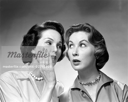 1950s 1960s TWO WOMEN GOSSIPING ONE WHISPERING INTO THE OTHER'S EAR