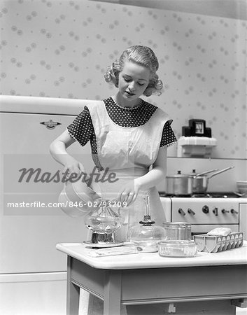 1930s WOMAN IN KITCHEN WEARING APRON MAKING BREAKFAST POURING WATER INTO COFFEE POT