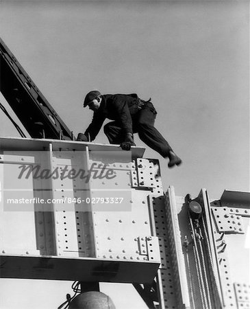 1930s CONSTRUCTION WORKER MAN ON STEEL GIRDER CLIMBING WEARING CAP