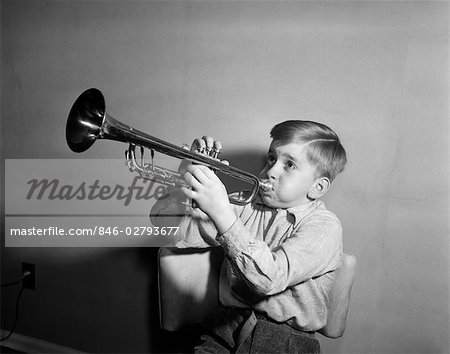 1950s BOY PLAYING TRUMPET HORN